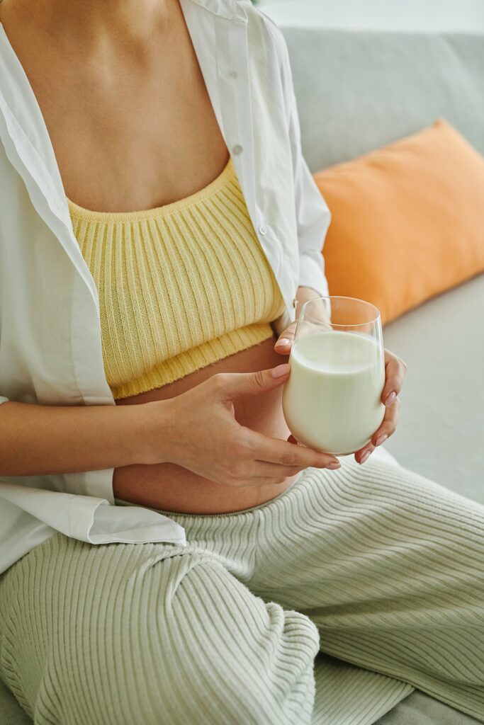 pregnant woman holding a glass of milk when to start taking prenatal vitamins