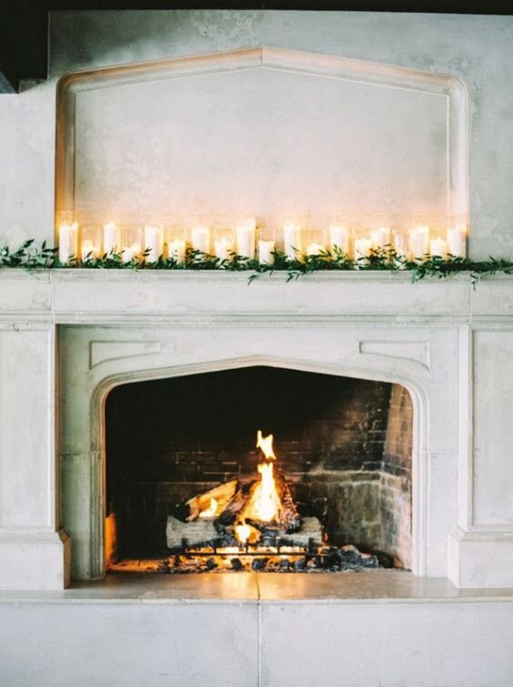 Christmas mantel over white brick fireplace with greenery and candles
