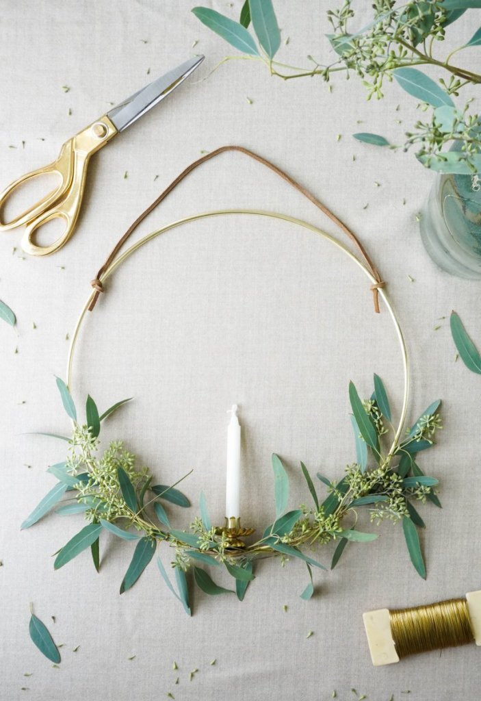 gold hoop wreath with fresh greenery and a candle in the center