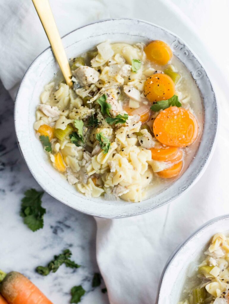 gluten free chicken noodle soup bowls on a marble background