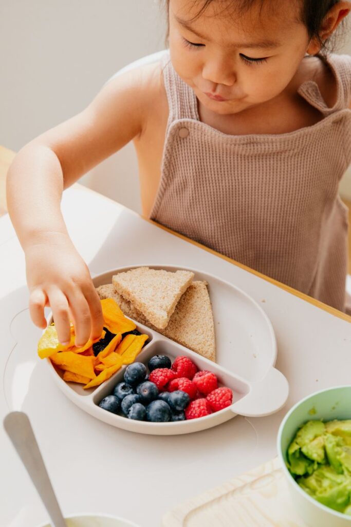 toddler picking at a plate of food